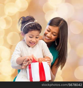 christmas, holidays, celebration, family and people concept - happy mother and little girl with gift box over beige lights background