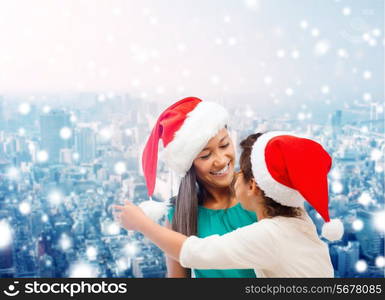 christmas, holidays, celebration, family and people concept - happy mother and little girl in santa helper hats over snowy city background