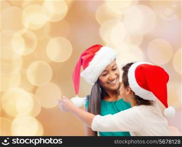 christmas, holidays, celebration, family and people concept - happy mother and little girl in santa helper hats over beige lights background