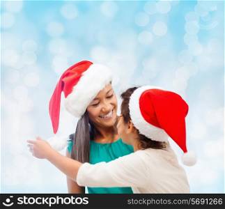christmas, holidays, celebration, family and people concept - happy mother and little girl in santa helper hats over blue lights background