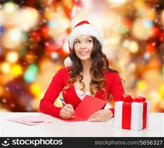 christmas, holidays, celebration, greeting and people concept - smiling woman in santa helper hat with gift box writing letter or sending post card over red lights background