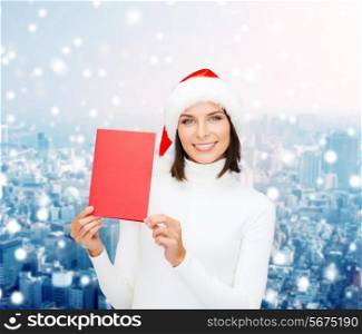 christmas, holidays, celebration, greeting and people concept - smiling woman in santa helper hat with greeting card over snowy city background
