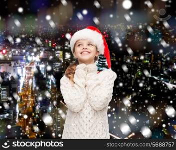 christmas, holidays, childhood and people concept - smiling girl in santa helper hat over snowy night city background