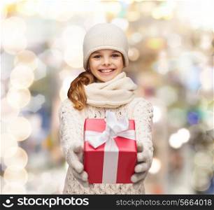 christmas, holidays, childhood, presents and people concept - dreaming girl in winter clothes with gift box over lights background