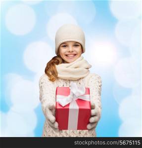 christmas, holidays, childhood, presents and people concept - dreaming girl in winter clothes with gift box over blue lights background