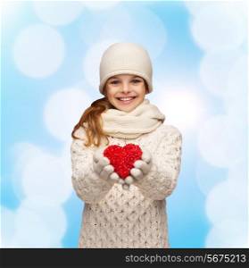 christmas, holidays, childhood, presents and people concept - dreaming girl in winter clothes with red heart over blue lights background