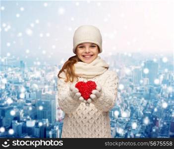 christmas, holidays, childhood, presents and people concept - dreaming girl in winter clothes with red heart over snowy night city background