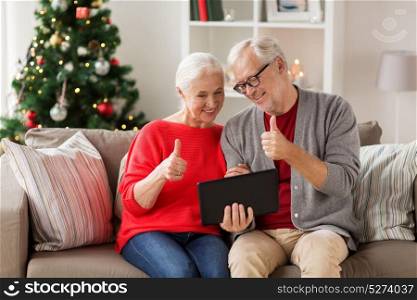 christmas, holidays, communication and people concept - happy smiling senior couple with tablet pc computer having video chat at home. happy senior couple with tablet pc at christmas