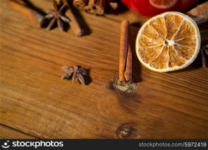 christmas, holidays, cooking and spice concept - close up of cinnamon, anise and dried orange on wooden board