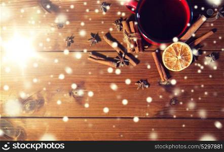 christmas, holidays, cooking and spice concept - close up of tea cup with cinnamon, anise and dried orange on wooden table from top. tea cup with winter spices on wooden table