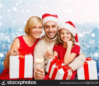 christmas, holidays, family and people concept - happy mother, father and little girl in santa helper hats with gift boxes over snowy city background