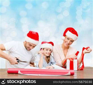 christmas, holidays, family and people concept - happy mother, father and little girl in santa helper hats with gift box and scissors over blue lights background