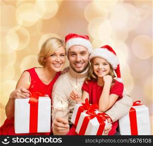 christmas, holidays, family and people concept - happy mother, father and little girl in santa helper hats with gift boxes over beige lights background