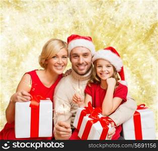 christmas, holidays, family and people concept - happy mother, father and little girl in santa helper hats with gift boxes yellow over lights background