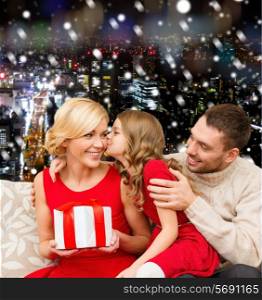 christmas, holidays, family and people concept - happy mother, father and little girl with gift box kissing over snowy night city background