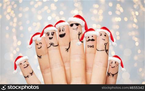 christmas, holidays, family, people and body parts concept - close up of two hands showing fingers with smiley faces and santa hats over lights background