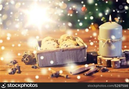 christmas, holidays, food and baking concept - close up of oat cookies in wooden box and cinnamon on table over lights. close up of christmas oat cookies on wooden table