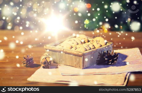 christmas, holidays, food and baking concept - close up of oat cookies in wooden box and cinnamon on table over lights. close up of christmas oat cookies on wooden table