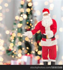 christmas, holidays, gesture and people concept - man in costume of santa claus over tree lights background