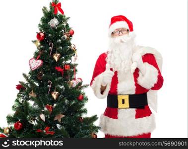 christmas, holidays, gesture and people concept - man in costume of santa claus with bag and christmas tree showing thumbs up