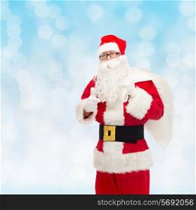 christmas, holidays, gesture and people concept - man in costume of santa claus with bag showing thumbs up over blue lights background