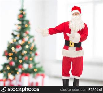 christmas, holidays, gesture and people concept - man in costume of santa claus over living room and tree background