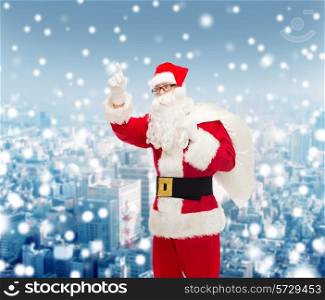 christmas, holidays, gesture and people concept - man in costume of santa claus with bag pointing finger up over snowy city background