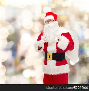 christmas, holidays, gesture and people concept - man in costume of santa claus with bag showing thumbs up over lights background