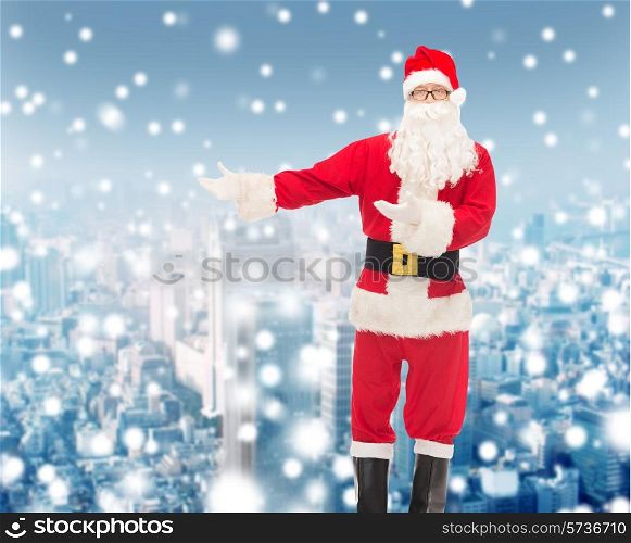 christmas, holidays, gesture and people concept - man in costume of santa claus over snowy city background