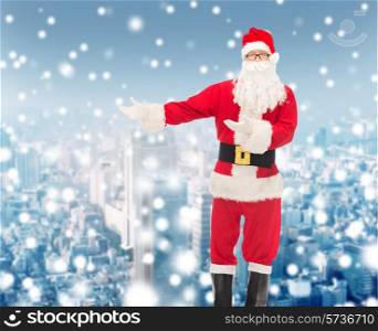 christmas, holidays, gesture and people concept - man in costume of santa claus over snowy city background