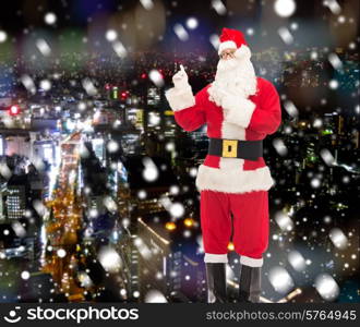 christmas, holidays, gesture and people concept - man in costume of santa claus pointing fingers over snowy night city background