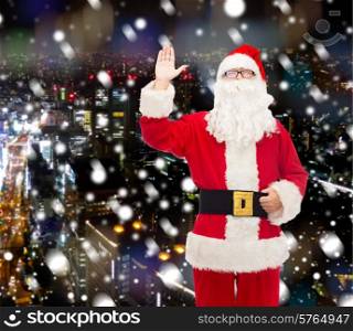 christmas, holidays, gesture and people concept - man in costume of santa claus waving hand over snowy night city background