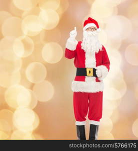 christmas, holidays, gesture and people concept - man in costume of santa claus pointing finger up over beige lights background
