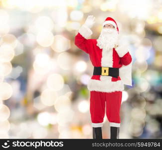 christmas, holidays, gesture and people concept - man in costume of santa claus with bag waving hand over lights background