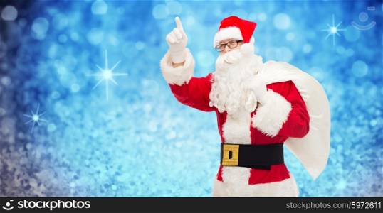 christmas, holidays, gesture and people concept - man in costume of santa claus with bag pointing finger up over blue glitter or lights background