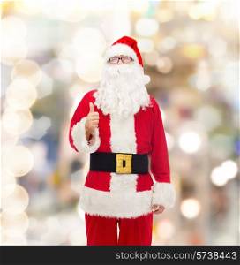 christmas, holidays, gesture and people concept- man in costume of santa claus showing thumbs up over lights background
