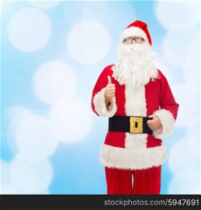 christmas, holidays, gesture and people concept- man in costume of santa claus showing thumbs up over blue lights background