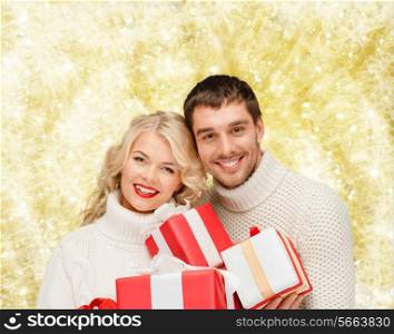christmas, holidays, happiness and people concept - smiling man and woman with presents over yellow lights background