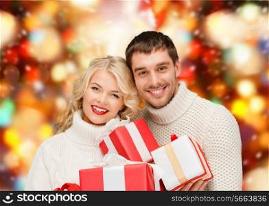 christmas, holidays, happiness and people concept - smiling man and woman with presents over red lights background