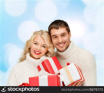 christmas, holidays, happiness and people concept - smiling man and woman with presents over blue lights background