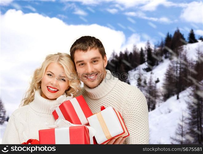 christmas, holidays, happiness and people concept - smiling man and woman with presents over snowy mountains background