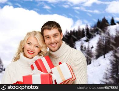 christmas, holidays, happiness and people concept - smiling man and woman with presents over snowy mountains background