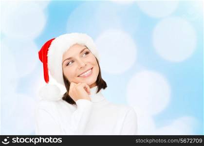 christmas, holidays, happiness and people concept - thinking and smiling woman in santa helper hat over blue lights background