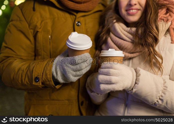 christmas, holidays, hot drinks and people concept - close up of happy young couple with coffee cups outdoors. close up of happy couple with coffee at christmas