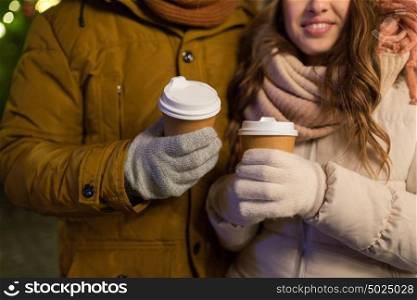 christmas, holidays, hot drinks and people concept - close up of happy young couple with coffee cups outdoors. close up of happy couple with coffee at christmas