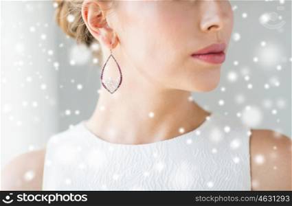 christmas, holidays, jewelry, people and luxury concept - close up of beautiful woman face with pearl earring over gray background and snow