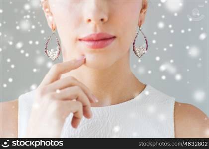 christmas, holidays, jewelry, people and luxury concept - close up of beautiful woman face with pearl earrings over gray background and snow