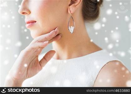 christmas, holidays, jewelry, people and luxury concept - close up of beautiful woman face with pearl earring over gray background and snow