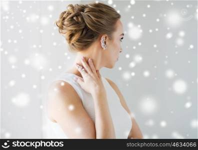 christmas, holidays, jewelry, people and luxury concept - close up of beautiful woman with golden ring and diamond earring over gray background and snow