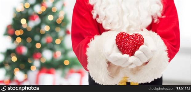 christmas, holidays, love, charity and people concept - close up of santa claus with heart shape decoration over living room with tree